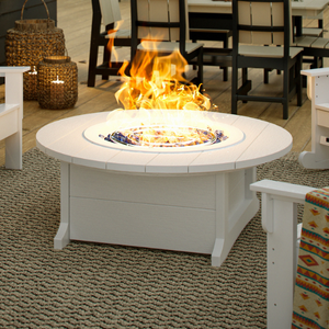 Round Fire pit table with flames in an outdoor setting with chairs and tables.