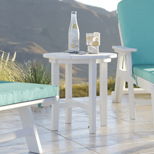Outdoor setting with white table and chairs with teal cushions, featuring a bottle and small container on the table.