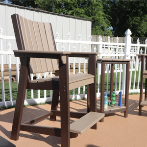 counter chair with a step on a deck with a white fence and greenery in the background