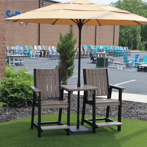 Outdoor furniture set with two counter chairs and a table under an umbrella on a grassy area.