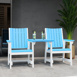 Two blue chairs and a matching table on a concrete patio with a gray wall and plant in the background.