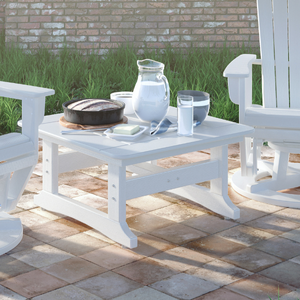 white coffee table on a concrete patio with grass in the background