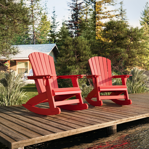 Two red Adirondack rocking chairs on a wooden deck with a forest background