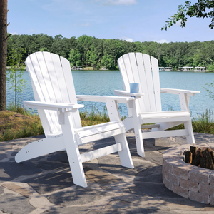 Two white Adirondack chairs by a lake with trees in the background.