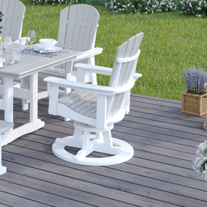 White outdoor swivel chairs and table set on a wooden deck with grass and plants in the background