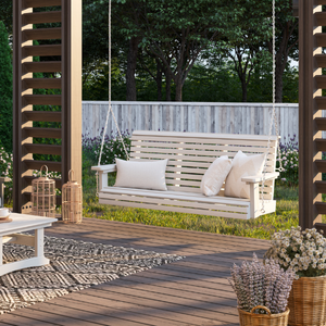 traditional swing with cushions on a wooden deck with plants and a fence in the background